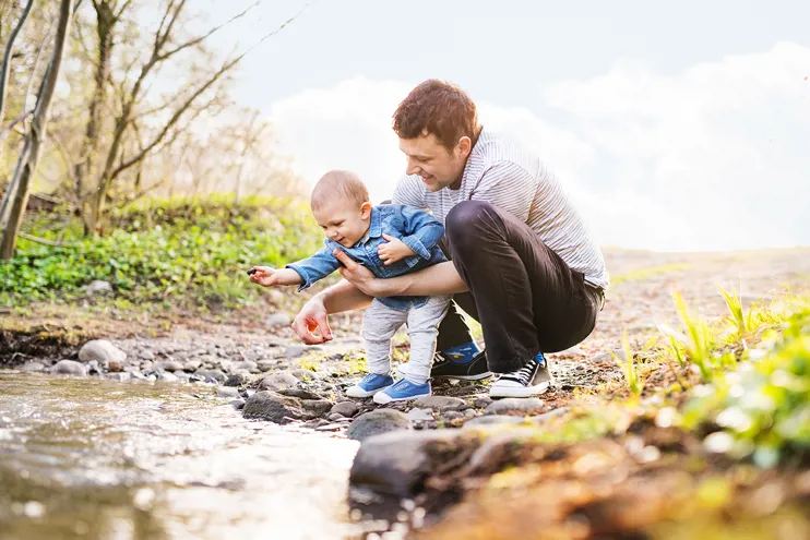 Man and young child playing near a stream